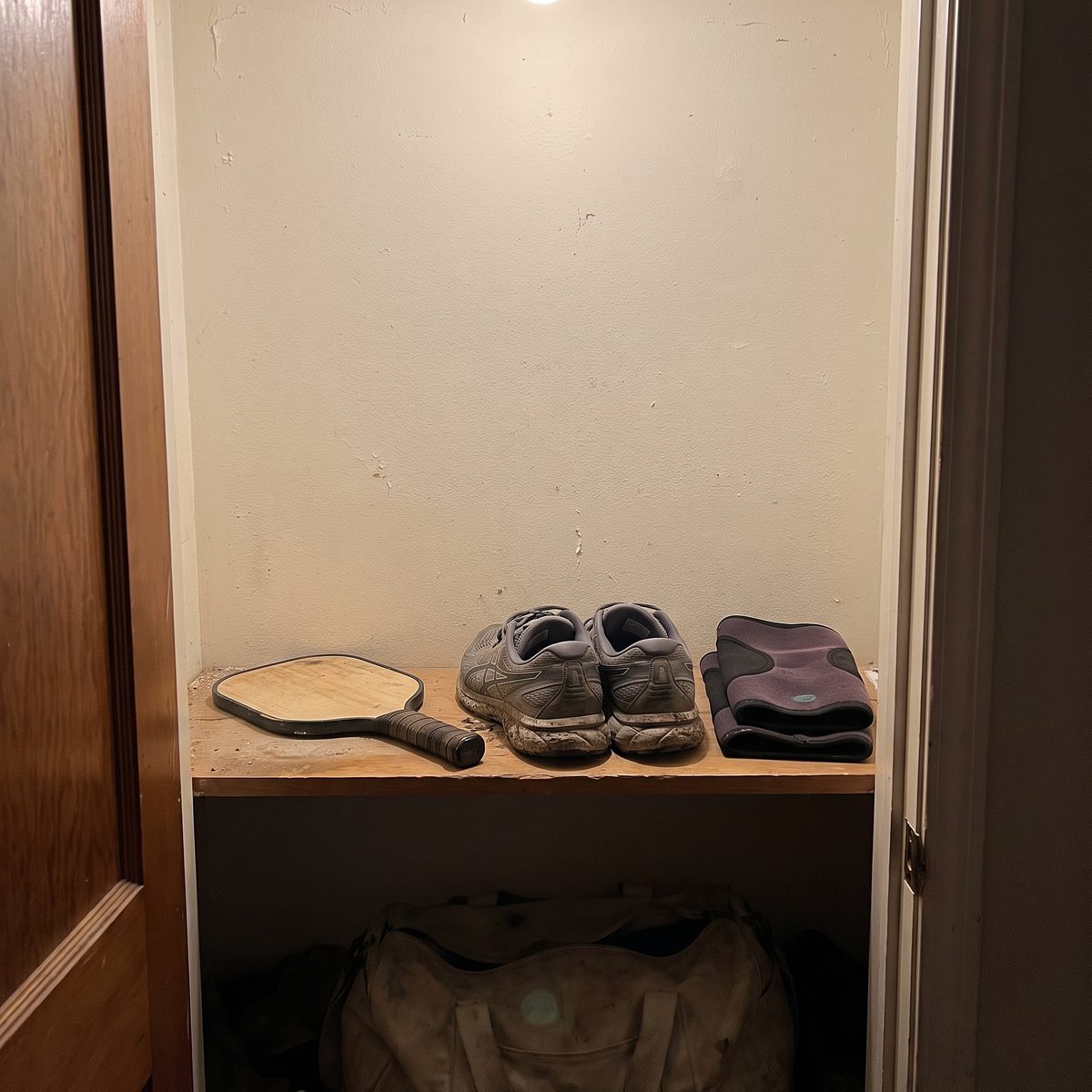 A closet shelf with walking shoes, a paddle and a gym bag put away